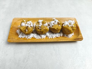 Traditional Indonesian Apem Cake With Palm Sugar and Grated Coconut in Wooden Plate