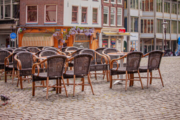 Empty wicker chairs arranged on a cobblestone square in a charming cityscape during a quiet afternoon