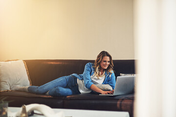 Obraz premium Relax, woman and smile with laptop in home for movie search, web surfing and weekend break. Space, happy person and typing with tech on sofa for film subscription, download series and chill afternoon