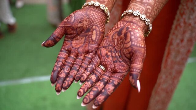 The bride is showing mehandi henna design on her hand at an Indian wedding