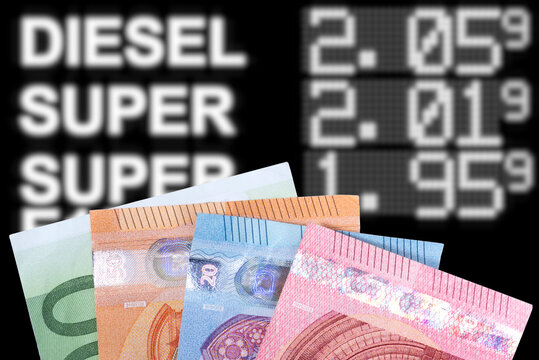 Euro Geldscheine und Preistafel an einer Tankstelle, die hohe Kraftstoffpreise anzeigt. 