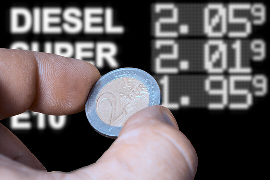 Eine Zwei-Euro-M&uuml;nze und Preistafel an einer Tankstelle, die hohe Preise f&uuml;r die Kraftstoffe anzeigt