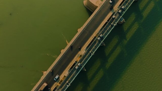 Kotri Barrage in Sindh, Pakistan with cars, bikes, and trucks passing by. The structure is surrounded by intense green water in the afternoon. Top-down aerial shot in 4K.