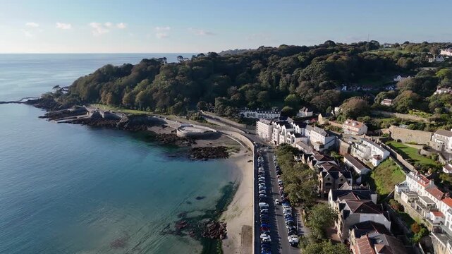 213
High drone footage over Havelet Bay St Peter Port Guernsey showing calm bay with clear sea,bathing pools and views over wooded cliffs in late afternoon sunshine with cloudless sky