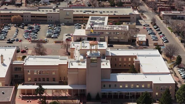 A high-angle drone perspective reveals the unique circular architecture of the New Mexico State Capitol. This 4K vista captures the heart of Santa Fe's government district.