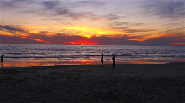 People silhouettes on Santa Monica beach at sunset with ocean
