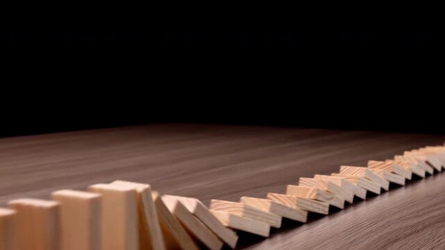 A row of wooden dominoes falling in a chain reaction, wooden block effect from continuous toppled block, prevention and development to stability, business strategy and risk management