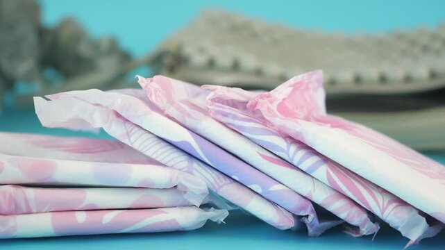 Close up motion footage of feminine hygiene products, daily pads or sanitary napkins on a light blue background
