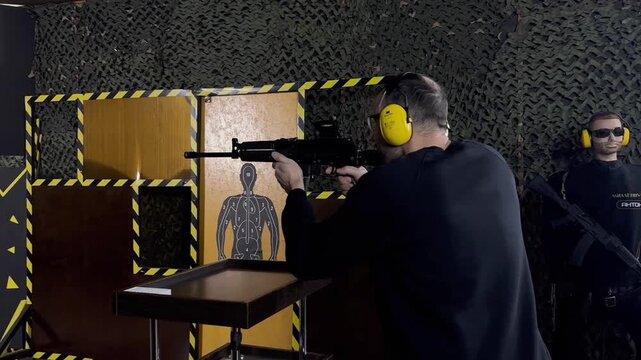 Man points a pistol at a target at shooting range. Shooter aims and fires at a target during shooting practice.