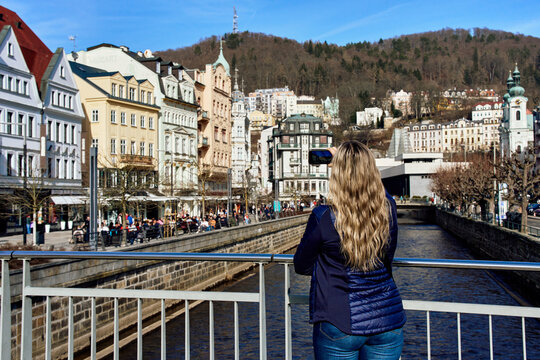 Tourist photographing colorful historic buildings along the Tepla river in the famous spa town of Karlovy Vary.
