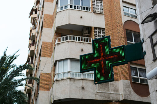 A sign on the building indicates the location of the pharmacy on a city street.