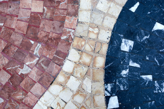 
a section of pedestrian path paved with small, multi-colored paving slabs