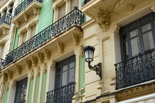 the facade of an old luxurious building with balconies and a lantern on the wall