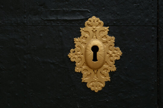 
Keyhole. An antique gold-colored lock on an old metal door.
