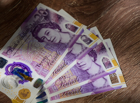 Fanned 20 Pound Notes Spread on Wooden Table