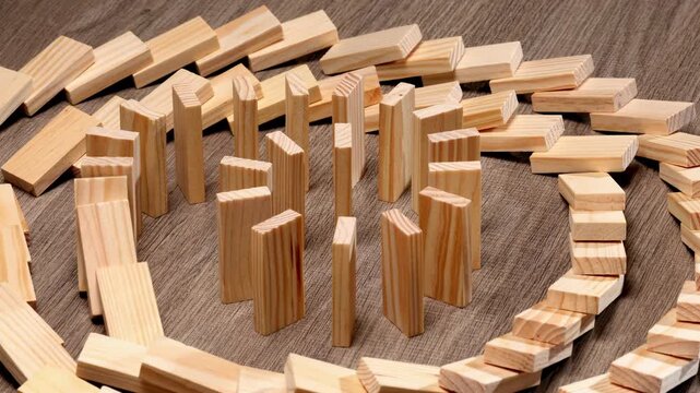 Circle domino effect concept, wooden dominoes falling in circular chain reaction, wooden block continuous toppled block, prevention, development to stability, business strategy, risk management