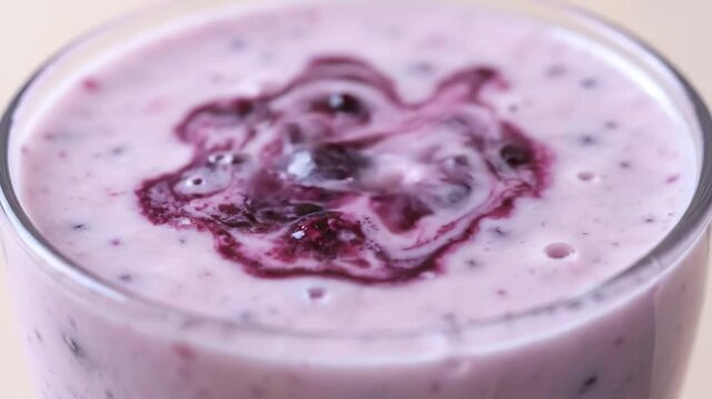 Refreshing Indian blueberry lassi drink in glass with ripe berries and mint garnish on rustic wooden table
