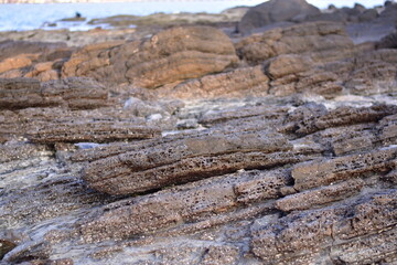 Layered black rough rocks, slate on the beach