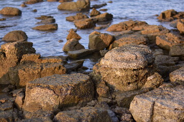 Fototapeta premium Layered black rough rocks, slate on the beach
