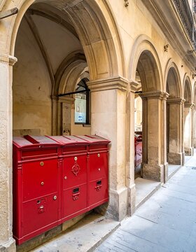 A row of red mailboxes under a long beige arched walkway