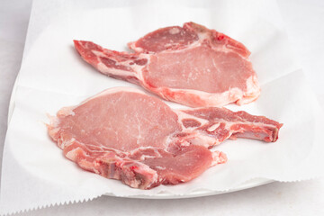 Fototapeta premium A raw cut of two ribeye meat slices on white butcher paper 