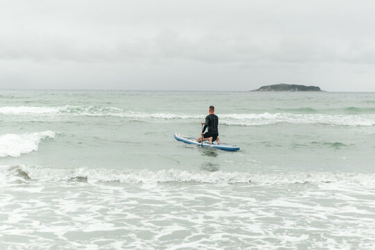 Man kneeling on paddleboard in the ocean waves.