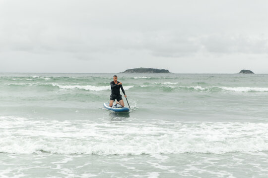 Man paddling on knees on paddleboard in the sea.
