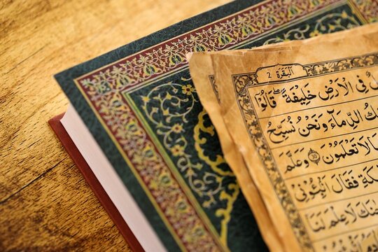 Pages of Al Quran Muslim holy book on table in mosque. Details of arabic calligraphy on islamic book close up. Concept of Islam religion and praying in arabic countries