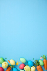 Fototapeta premium Easter bottom border with colorful eggs, carrots and chicks on blue background with copy space