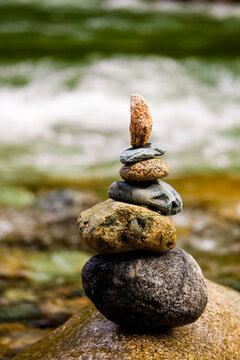A stack of small rocks balanced on top of each other by a river.