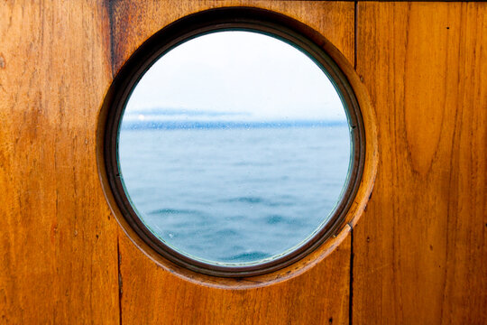 Porthole window on a ferry, with a wooden surround.