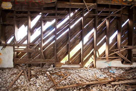 A derelict house, abandoned property, rotten broken beams and joists, sunlight coming through the walls.