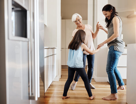 Mom, grandma and dancing with child in kitchen for bonding, love and holding hands with generations. People, grandmother and daughter with girl, connection and excited with play in happy family home