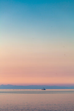 A purse seiner fishing vessel at dusk on the Strait of Juan de Fuca trailing a large net.