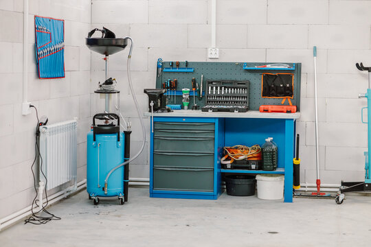 Interior of a modern car service station with a blue workbench and oil drainage equipment. Professional automotive workshop garage with organized tools, toolbox, and repair equipment.