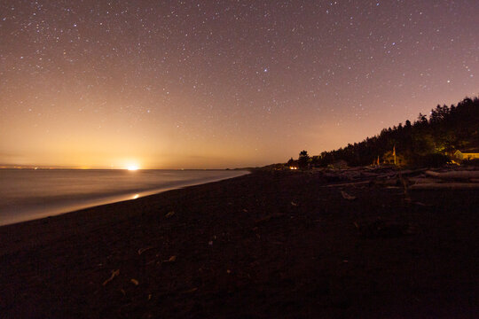 Star filled sky and the sun emerging on the horizon above Freshwater Bay, Port Angeles