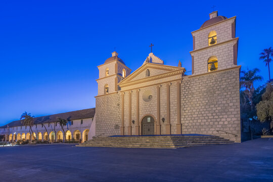 Santa Barbara mission, an 18th century Spanish colonial style church building at dusk, pediment and bell towers.