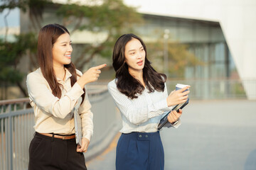 Obraz premium businesswomen team reviewing and discussing a business project outside office building.