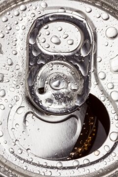 Macro image of an open aluminum can with water droplets on the surface. Refreshing, cold drink concept with metallic texture.