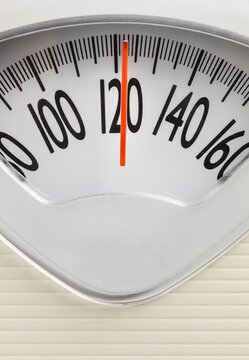 Analog bathroom scale showing 120 pounds. Health, fitness, or weight management concept on a clean, minimal background.