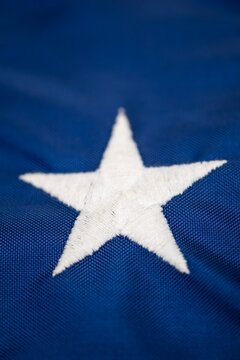 Detailed macro image of a single embroidered white star on the blue field of the American flag