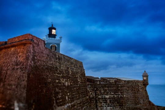 Lighthouse of Castillo San Felipe del Morro glows at twilight above the historic stone walls of the 16th-century fortress,  San Juan National Historic Site, UNESCO World Heritage site 