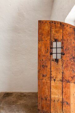 An old wooden door with iron grate detail stands partially open inside Castillo San Felipe del Morro in San Juan. 