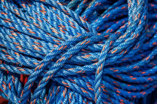 Close-up of coiled blue nylon rope with orange strands, tightly bundled and vibrant in color.
