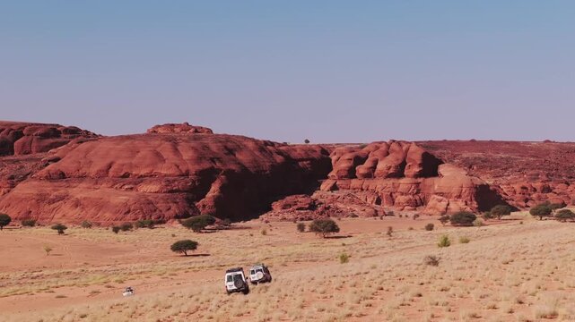 Jeep Offroad in Sahara Desert, Driving Through Sand Dunes and Rocky Landscape
4x4 Convoy From Drone with Red Mountains in the Background, Telephoto Aerial