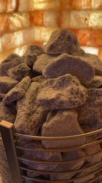 Electric sauna heater with glowing hot stones, surrounded by walls lined with therapeutic rock salt for a healing, steamy atmosphere.