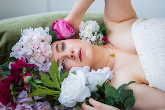 Woman in White Smocked Strapless Dress Laying with Head in Flowers