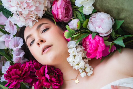 Woman Wearing Necklace Laying Down Amongst Vibrant Pink Floral Bouquet