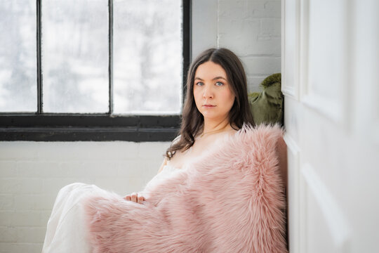 Woman Sitting by Window with Pink Shaggy Blanket