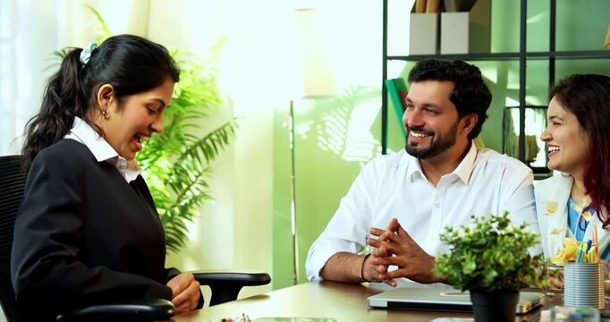 Indian married young couple receiving key from executive lady in cozy office as wife shows extreme excitement and happiness during the successful handover of their new home or property